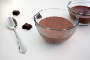 Vérine de mousse au chocolat noir sur une nappe blanche.